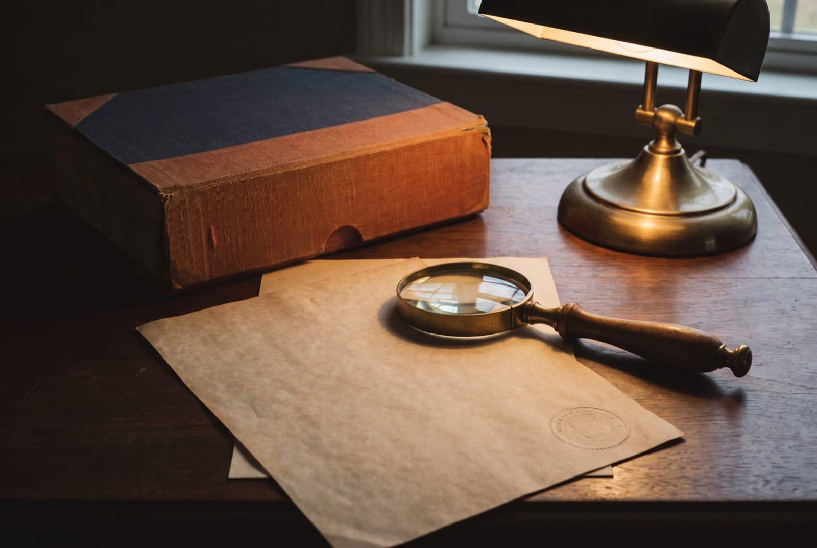 A completed agreement with an embossed seal, a brass magnifying glass resting across it.