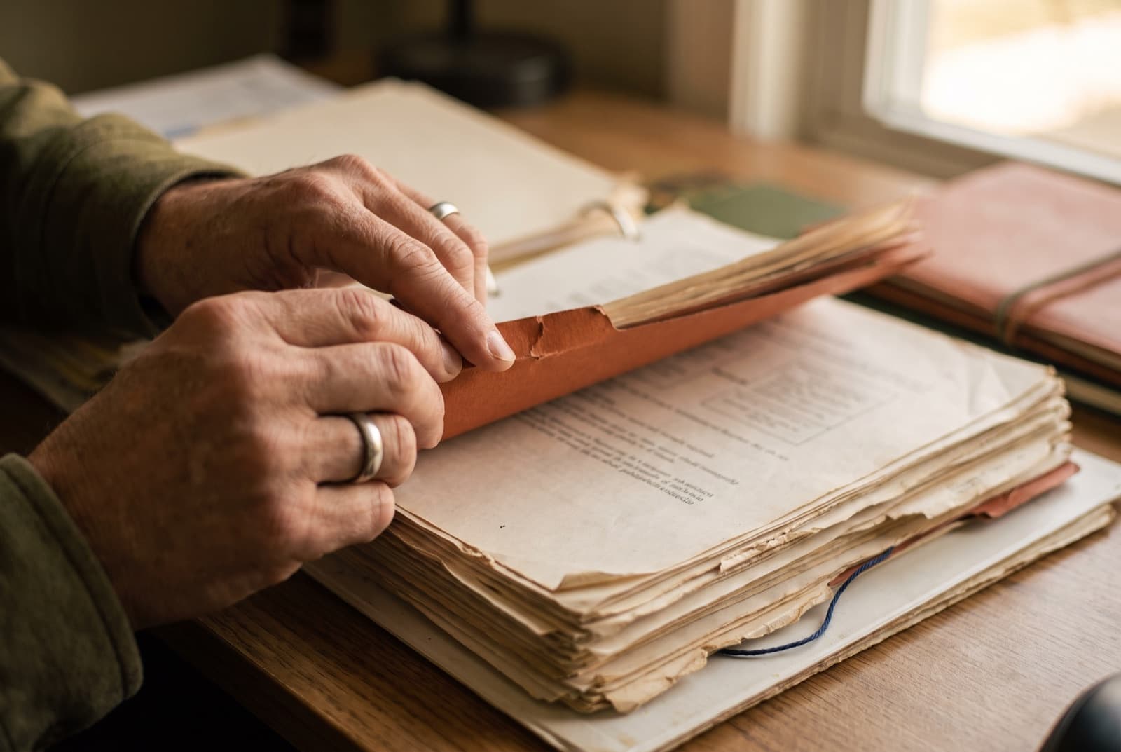 Hands leafing through a thick ring binder, holding a tab divider open.